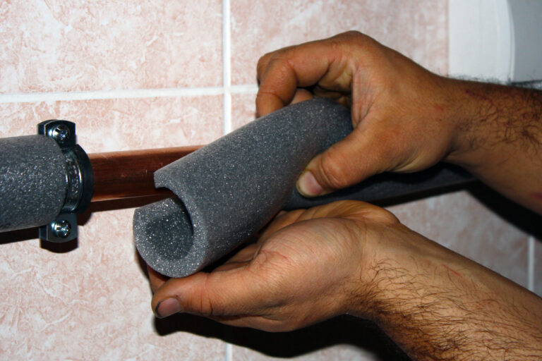Man putting foam insulation on an exposed pipe